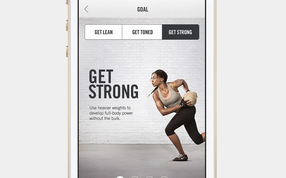 A fitness app screen displays a woman in athletic wear holding a weighted ball in a lunge stance. The text reads GET STRONG with a description about using heavier weights to build power. Three goals are selectable: Get Lean, Get Toned, Get Strong.